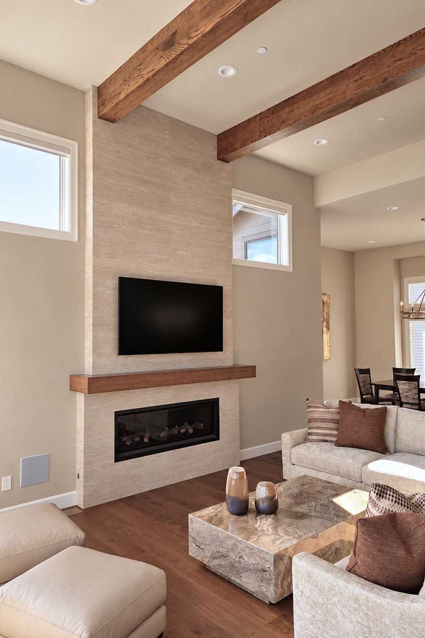 Fireplace wall in textured stone-look tile with a floating wood mantel, wall-mounted TV, and wood ceiling beams.